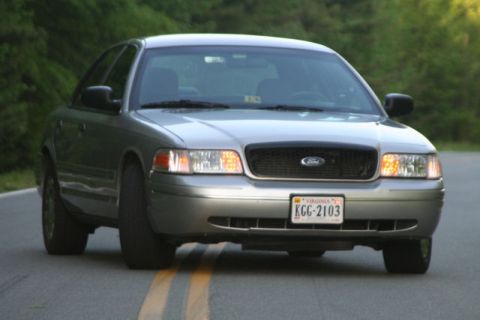 2004 Ford Crown Victoria - This 2004 Ford Crown Victoria is shown from the front on a paved road with yellow lines.