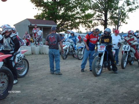 1995 Ford Probe - Racers and crew prepare for a flat track motorcycle event, with several bikes lined up.