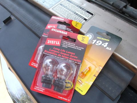 1992 Ford F-350 - Various Sylvania automotive bulbs, including 3157 LL long life lamps and 194 NA side marker bulbs, are displayed on a vehicle's engine bay.
