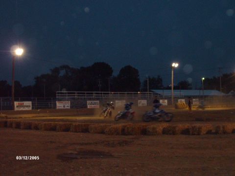 1995 Ford Probe - Motorcycle race in progress on a dirt track under stadium lights at dusk.
