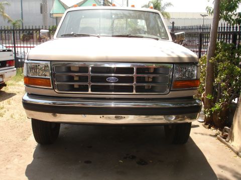 1992 Ford F-350 - The front grille and headlights of a tan Ford F-350 pickup truck are visible.