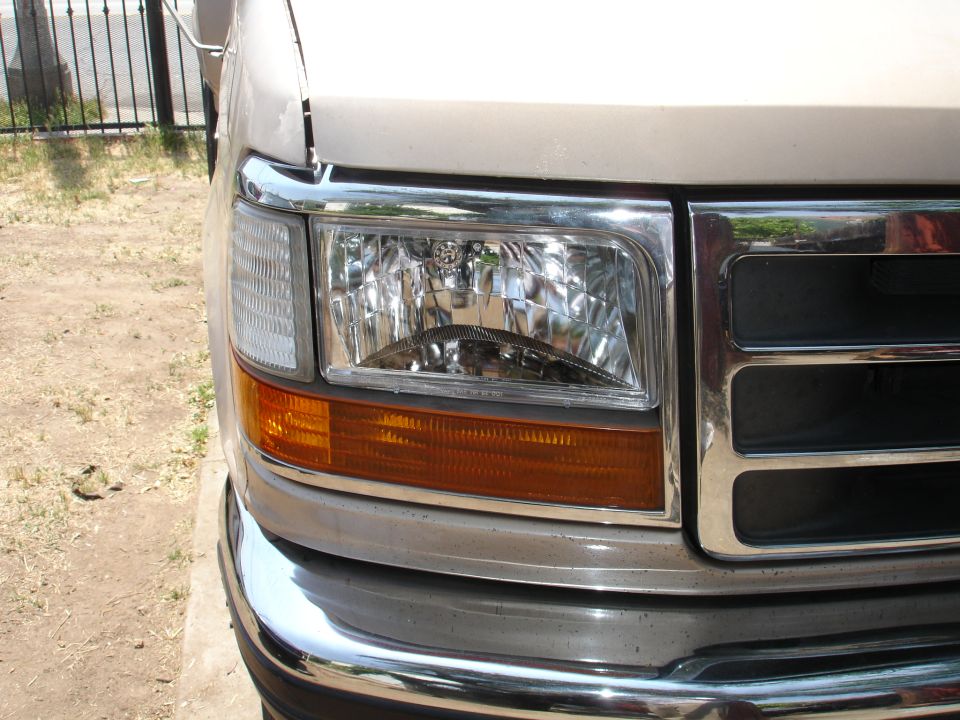 Close-up of headlight, amber turn signal and chrome grille on a tan pickup