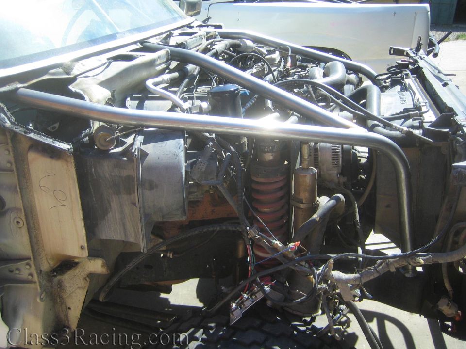 Engine bay of a project truck with red coilover, tube chassis bracing and wiring