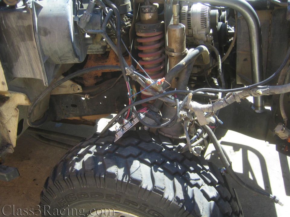 Lower engine and front axle area with red coilover, wiring and an off-road tire