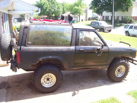 1989 Ford Bronco II - A 1989 Ford Bronco II is parked in a driveway with other vehicles visible in the background.
