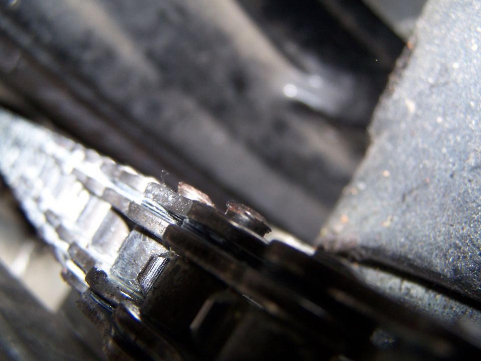 Close-up of greasy motorcycle drive chain on rear sprocket