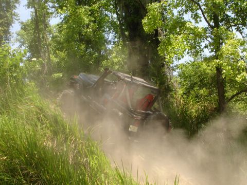 1989 Ford Bronco - An off-road vehicle navigates a dusty, wooded trail.