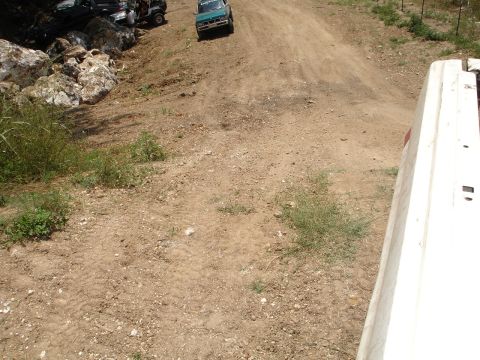 1989 Ford Bronco - Several vehicles are visible on a dusty, off-road path with large rocks scattered around the terrain.