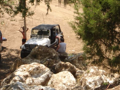 1989 Ford Bronco - A white Jeep Wrangler is seen parked on a rocky trail with several people nearby, suggesting an off-road excursion.