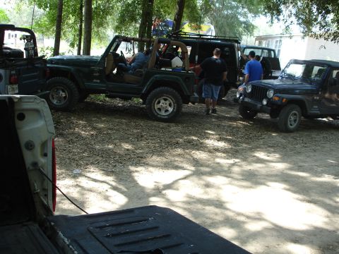 1989 Ford Bronco - Multiple Jeeps are parked together in a shaded, outdoor area, suggesting a gathering or event.