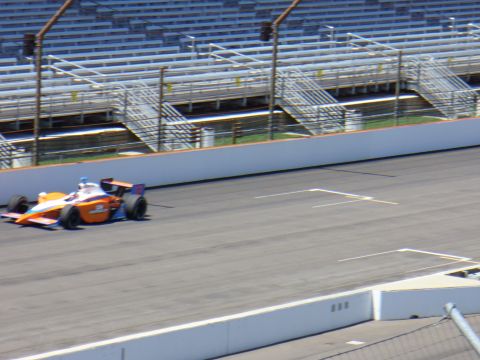 1991 Ford Probe - An IndyCar race car speeds around a track with empty grandstands visible.