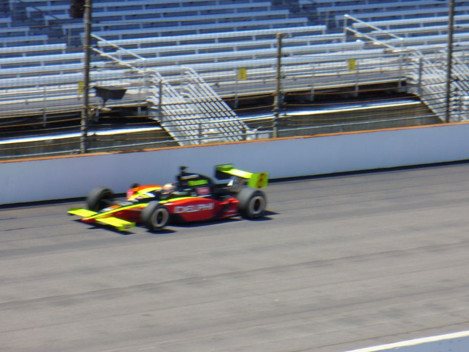 Red and yellow open-wheel race car with green accents on track
