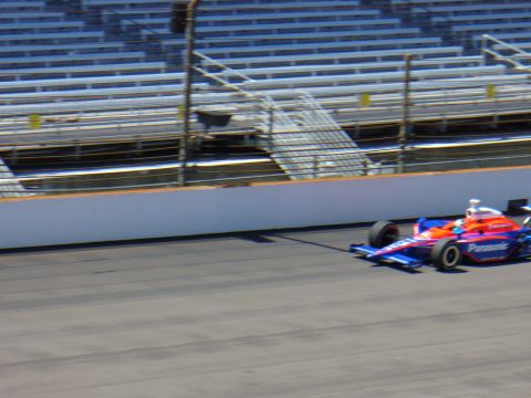1991 Ford Probe - A race car speeds along the track in front of empty grandstands.