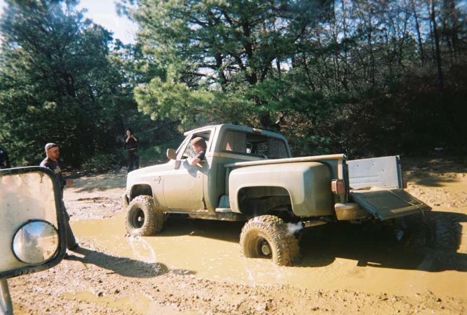 Olive green pickup truck stuck in mud with tailgate down