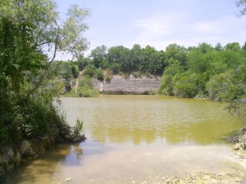 1989 Ford Bronco - A scenic view of a lake surrounded by trees and rocky cliffs, with a watermark at the bottom right.