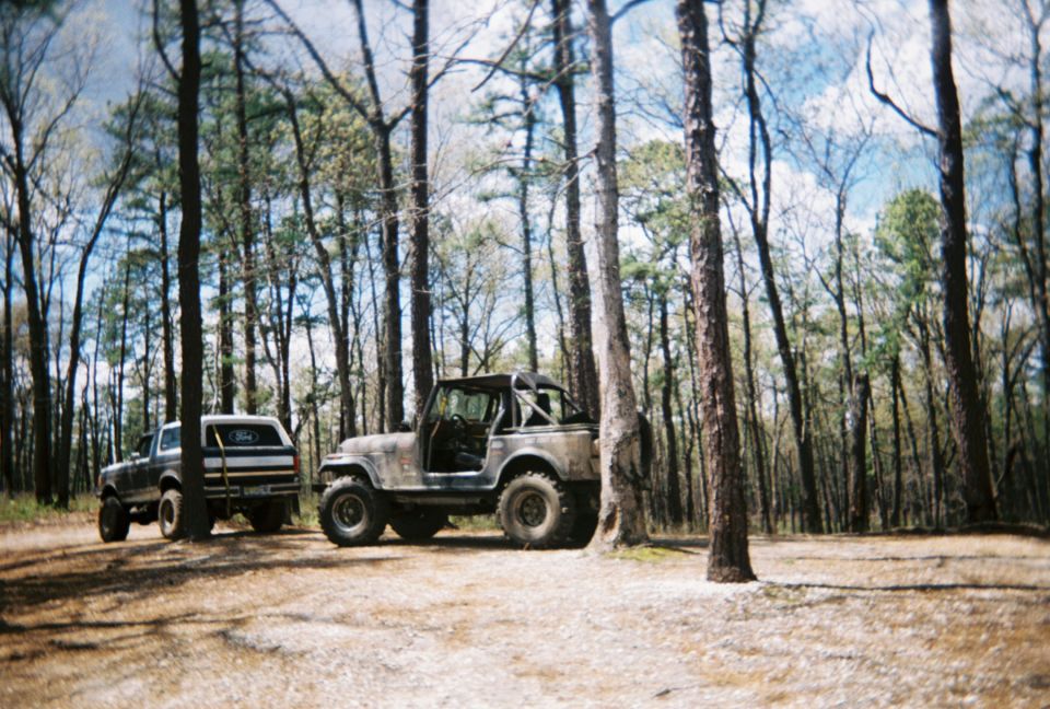 Ford Bronco parked next to a Jeep CJ in a wooded area