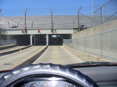 1991 Ford Probe - View from inside a vehicle as it passes through a tunnel beneath stadium seating at a racetrack.