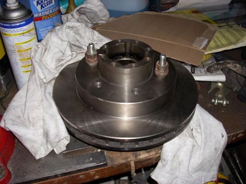 2000 Chevrolet Tahoe - A brake rotor and hub assembly sits on a workbench, surrounded by shop rags and automotive fluids.
