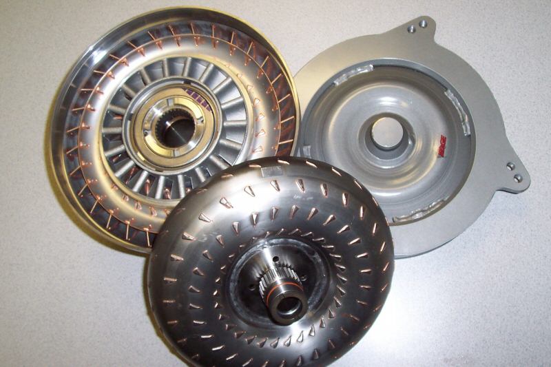 Three automatic transmission torque converters and a bellhousing on a bench