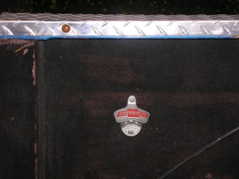 1979 Chevrolet C/K Pickup - A Chevrolet-branded bottle opener is attached to a dark surface, possibly a toolbox or truck bed.