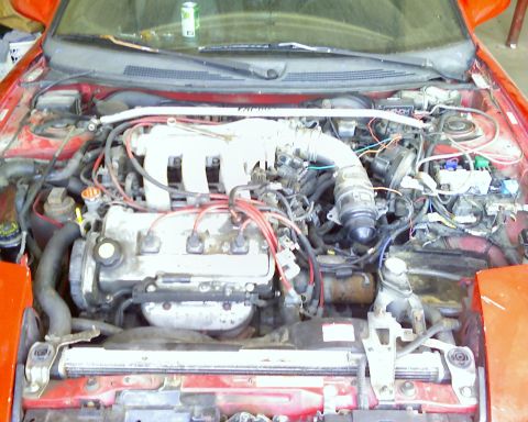 1993 Ford Probe - The engine compartment of a red car is shown with various mechanical parts and wiring.