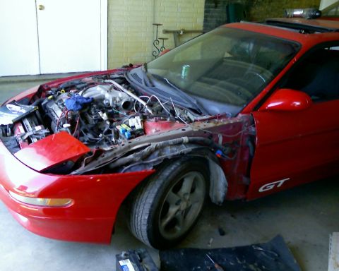 1993 Ford Probe - This red car, possibly a Ford Probe GT, is shown with its engine compartment open and front fender removed.