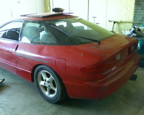 1993 Ford Probe - The rear of a red 1993 Ford Probe GT is visible, parked indoors with a sunroof and a roof-mounted accessory.