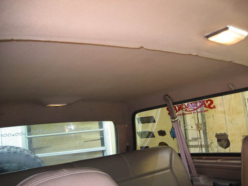 Interior shot of a vehicle's headliner, seats, and rear window with stickers