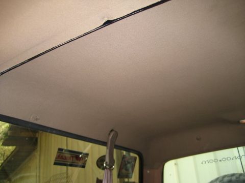 1995 Ford Bronco - The headliner of the vehicle shows some wear and tear, with stickers visible on the rear window.