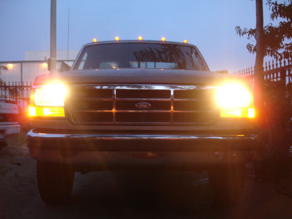Ford pickup head-on at dusk, headlights on, chrome grille and five amber cab clearance lights lit