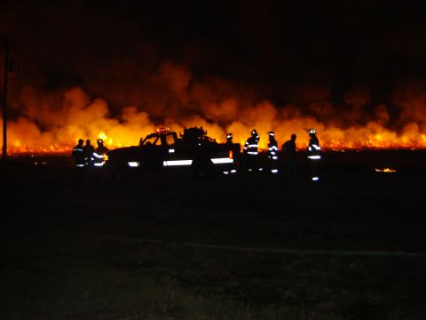 1998 Ford Crown Victoria - Firefighters respond to a large field fire at night, with a tow truck present at the scene.