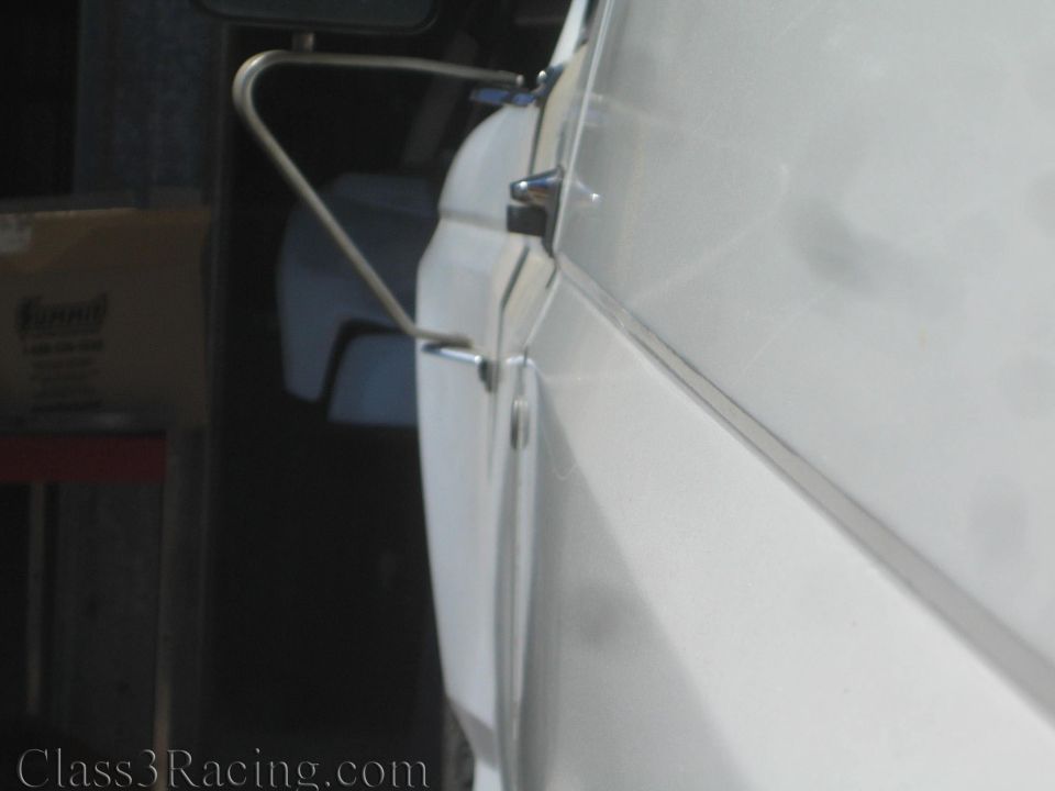 Extreme close-up of a tubular bracket along a white body panel edge