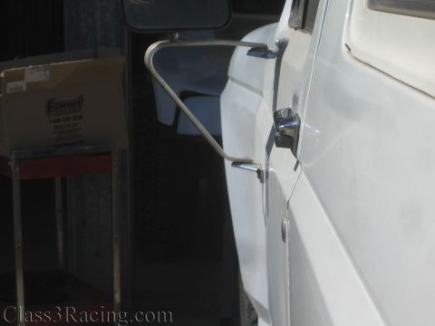 1990 Ford Bronco - chrome tubular mirror bracket mounts to the door area of a white truck in a shop, with a Summit Racing box visible at left.