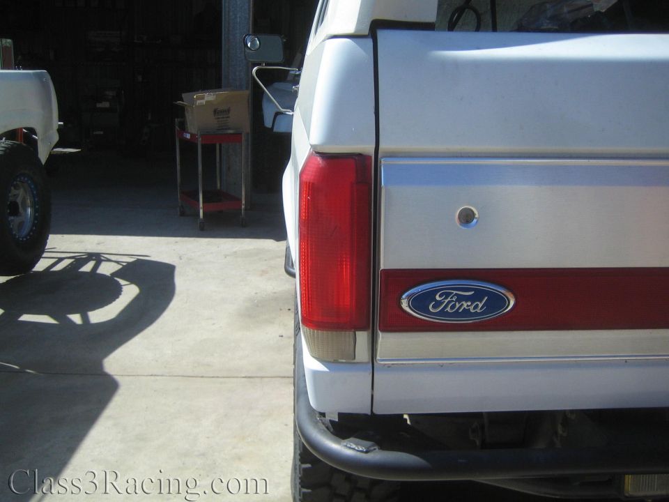 Rear of a white lifted Ford SUV with Ford oval badge on the two-tone tailgate
