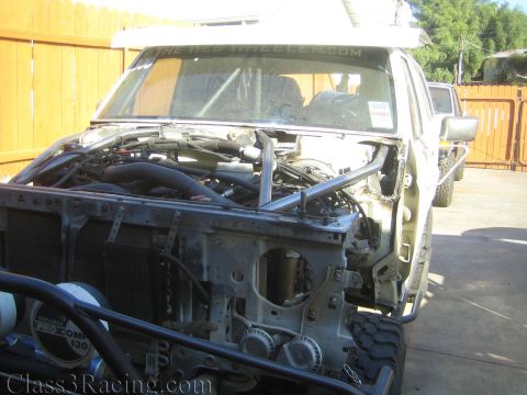 1990 Ford Bronco - stripped truck front end with hood off, exposing the engine and radiator, with Pro Comp lights mounted below.