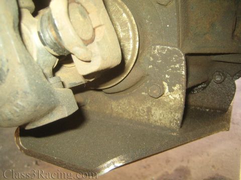 1990 Ford Bronco - grease-covered suspension or axle assembly with a bolt and welded steel bracket shown in close detail.