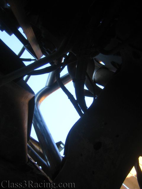 1990 Ford Bronco - fabricated tubular chassis with crossing steel tubes and an exhaust pipe is silhouetted against the sky from below.