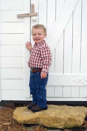 1998 Jeep TJ - A young boy smiles while standing on a rock in front of a white barn door.