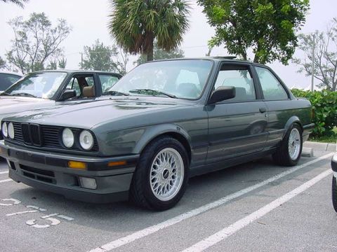 1989 BMW 3 Series - A dark green 1989 BMW 3 Series coupe is parked in a lot, showing its distinctive front grille and alloy wheels.