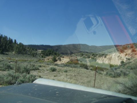 1967 Ford Bronco - Looking out from the hood of a vehicle towards a vast, arid landscape under a clear blue sky. The Supermotors logo is visible in the lower…