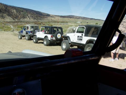 1967 Ford Bronco - A line of Jeeps are parked on a dusty road, with a person standing near the front Jeep.