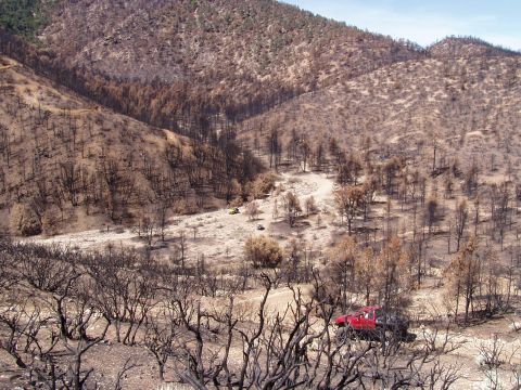 1967 Ford Bronco - Several vehicles are visible in a valley with hillsides covered in burnt trees and brush.