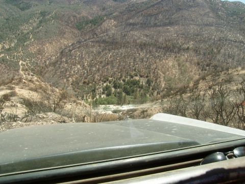 1967 Ford Bronco - View from inside a vehicle looking out over a desolate, fire-scarred mountain range towards a distant riverbed.