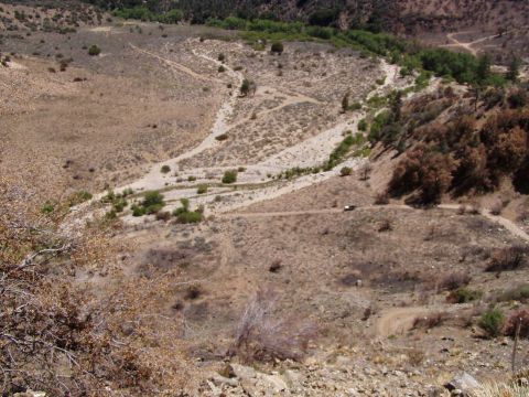 1967 Ford Bronco - A lone vehicle navigates a winding dirt path through a , arid canyon environment.