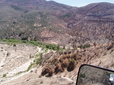 1967 Ford Bronco - A view of a , fire-affected mountain terrain seen from a vehicle's side mirror.