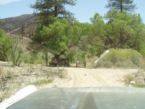 1967 Ford Bronco - An off-road vehicle is parked in a natural setting, with people gathered at a picnic table nearby.