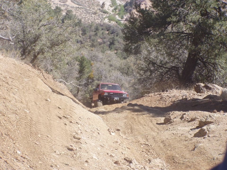 Red off-road vehicle climbing a dirt hill