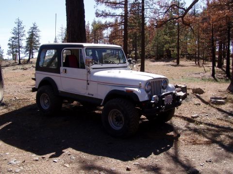 1967 Ford Bronco - White Jeep CJ-7 with black hardtop and aftermarket bumper sits off-road.