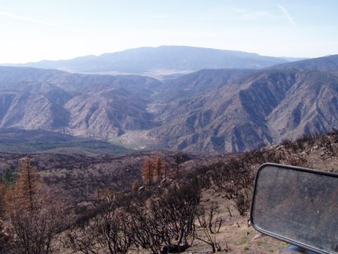 1967 Ford Bronco - A scenic view of a valley and mountains, with burnt trees in the foreground and a side mirror visible.