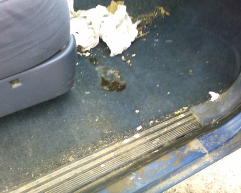 1989 Ford Bronco - The interior of a vehicle shows a dirty floor with trash and stains.